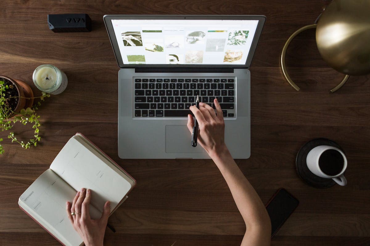 Overhead view of person working on laptop with notebook and coffee