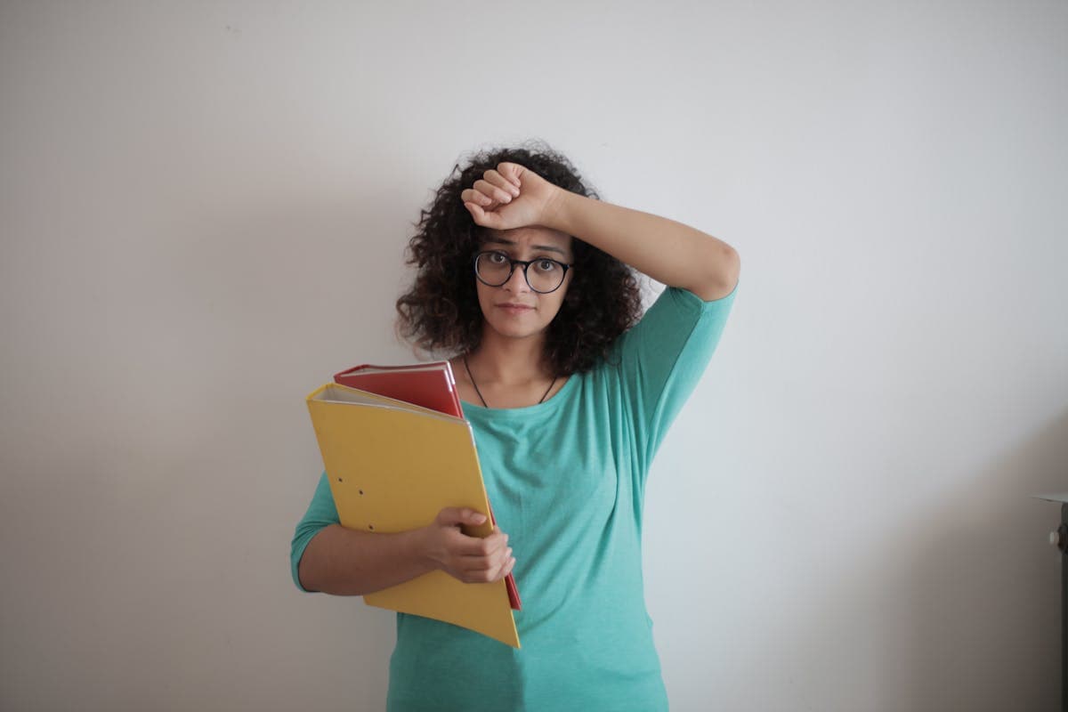 Overwhelmed worker holding folders and paperwork