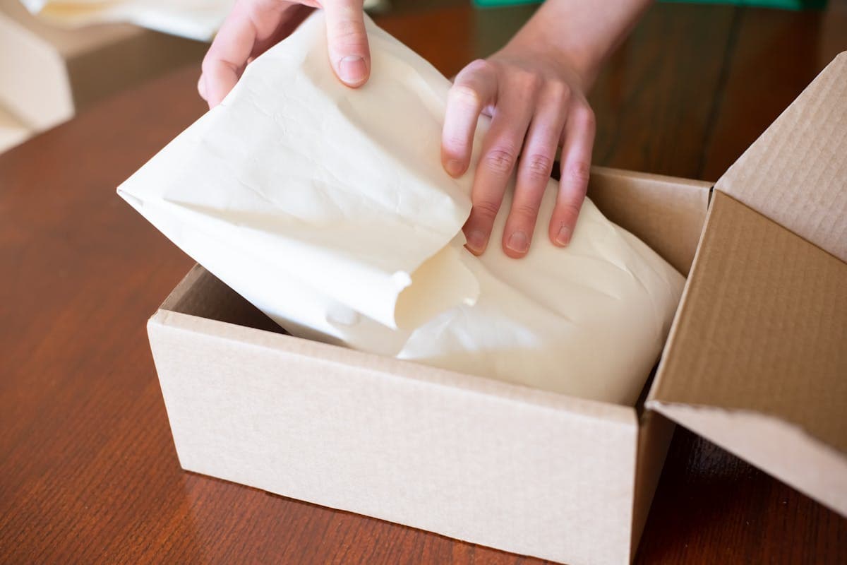 Hands packing a product into a cardboard shipping box